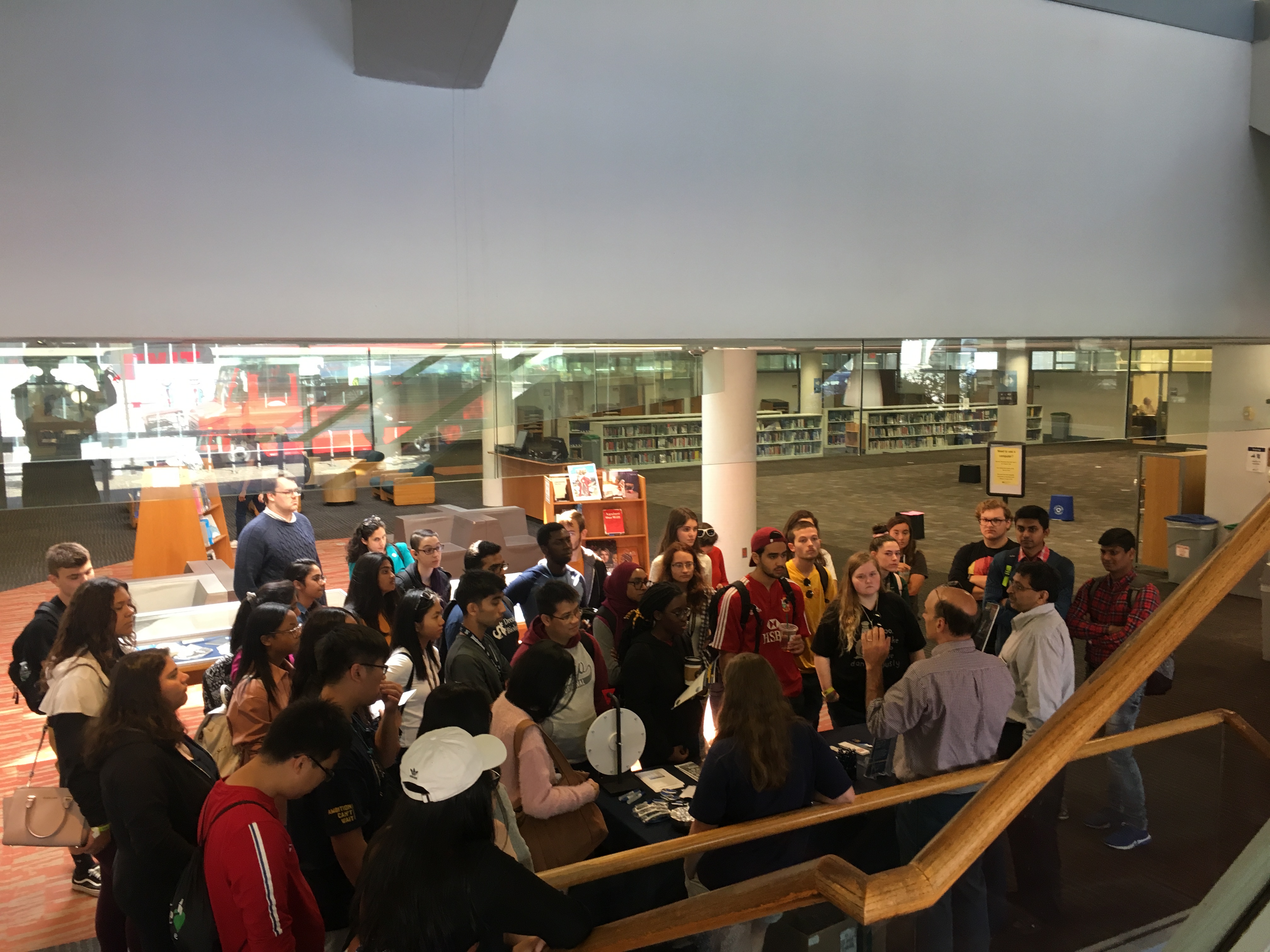 A group of 30 students stand in the first floor of the Hagerty Library